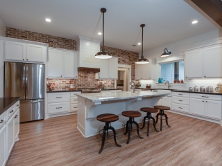 The Moore Project's kitchen by LaFollette Custom Homes features white cabinets and a brick backsplash.