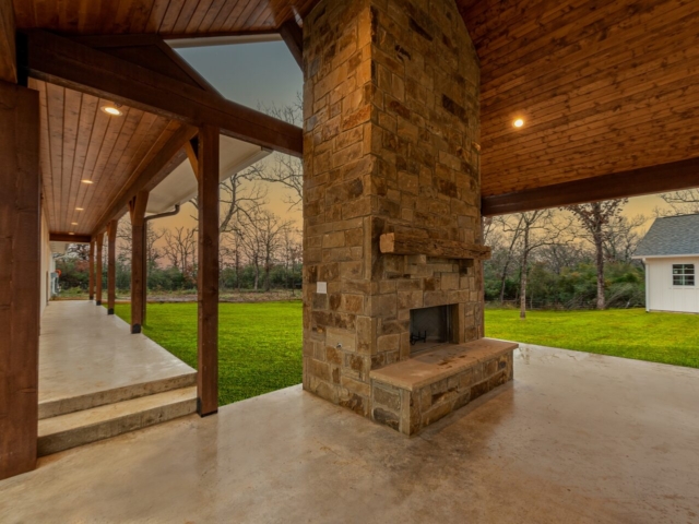 Stunning stone fireplace and carport of the Barnwood Project by LaFollette Custom Homes