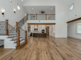 Living room of the Oak House Project by LaFollette Custom Homes, with stunning staircase and wood flooring.