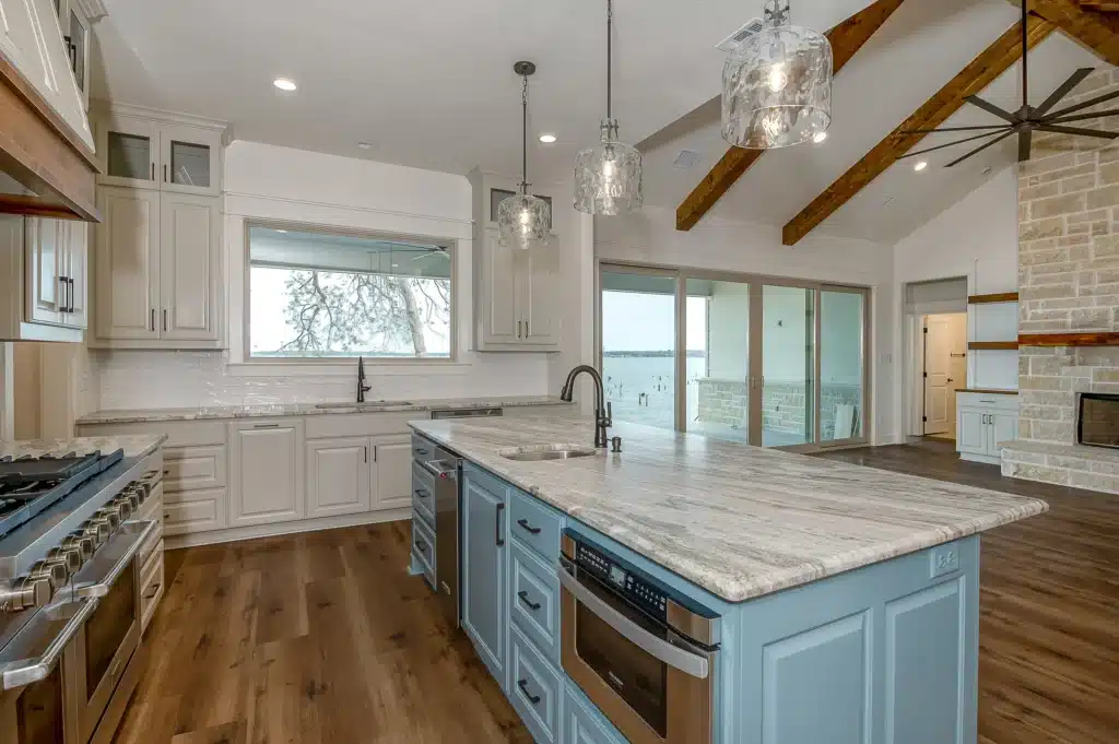 Current image: Trending kitchen features with white counter tops, blue cabinets, white walls, and brow wood flooring.