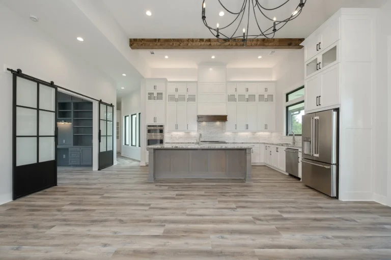 Modern kitchen with white cabinets, gray island, stainless steel appliances, and sliding glass barn doors.