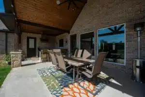 Covered patio with dining table, outdoor ceiling fan, and brick walls, designed for year-round outdoor living.