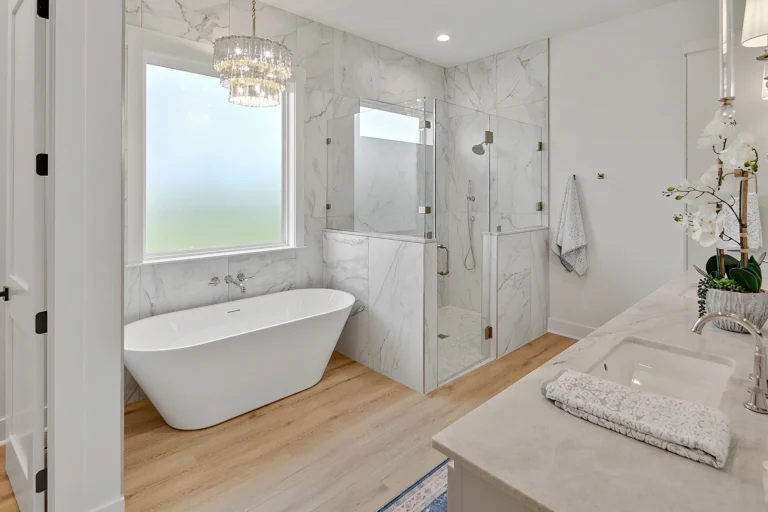 Functional Beauty in a Custom Home bathroom with white tub and sink, wooden floors, and a window above the bathtub.