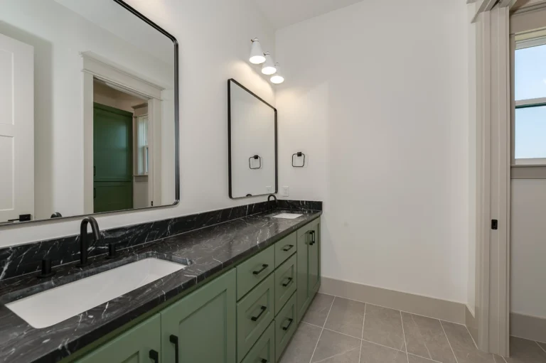 Designing a Custom Home for Every Season of Life - LaFollette Custom Homes bathroom with green vanity, black countertop, and modern fixtures.